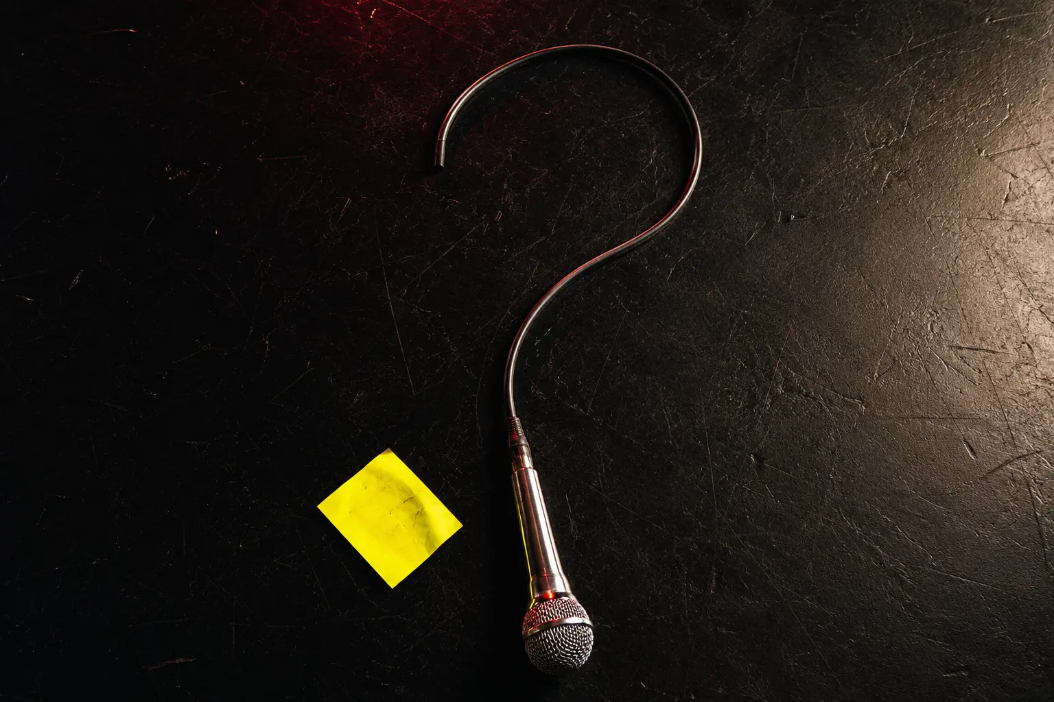 A stage microphone cable twisted into a question mark under warm light